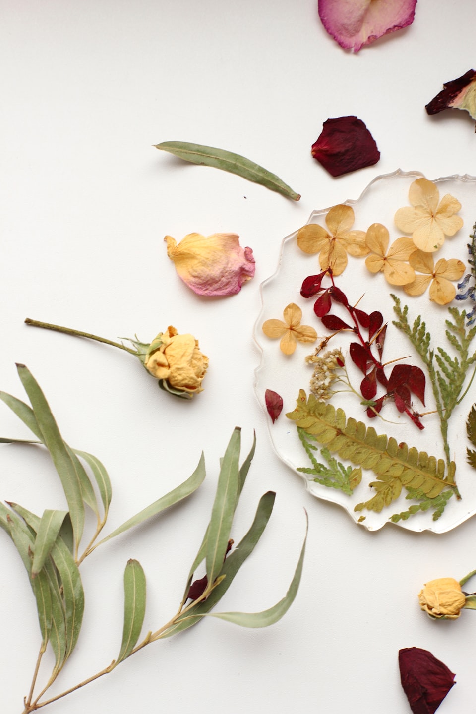 Dried botanical elements and a resin flower ornament on white.