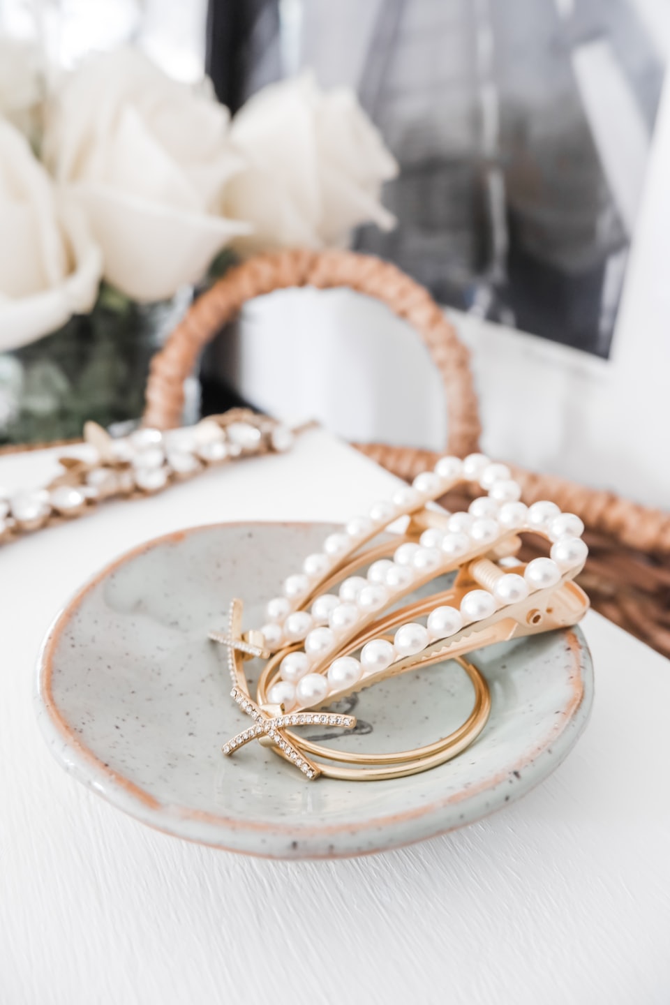 Gold hair clips and rings resting in a ceramic dish.