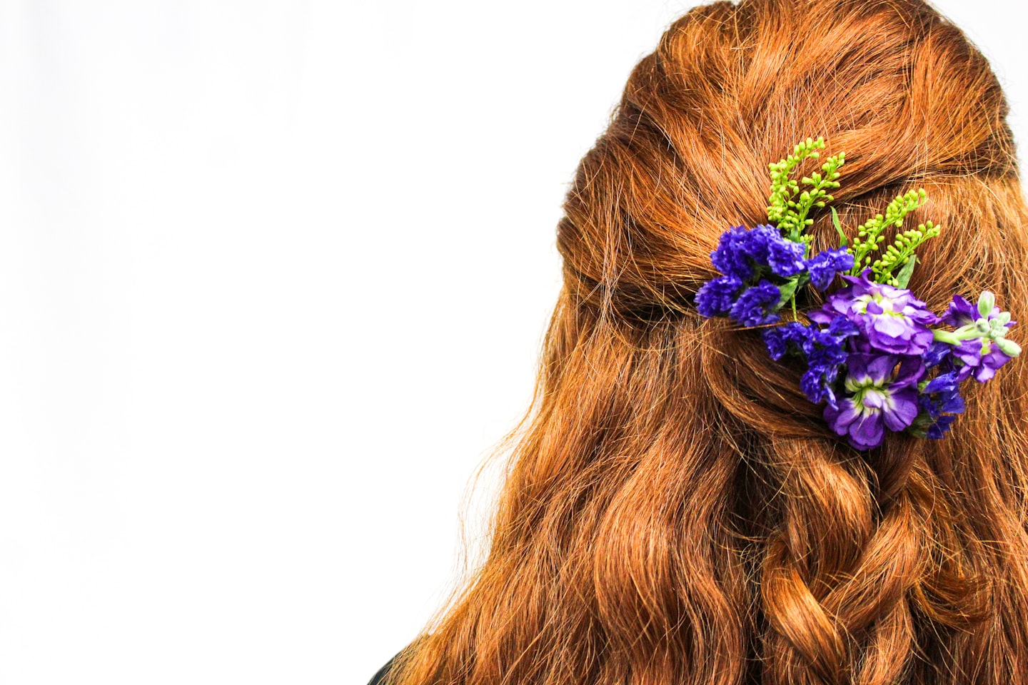 Wavy reddish-brown hair styled with a flower hair clip.